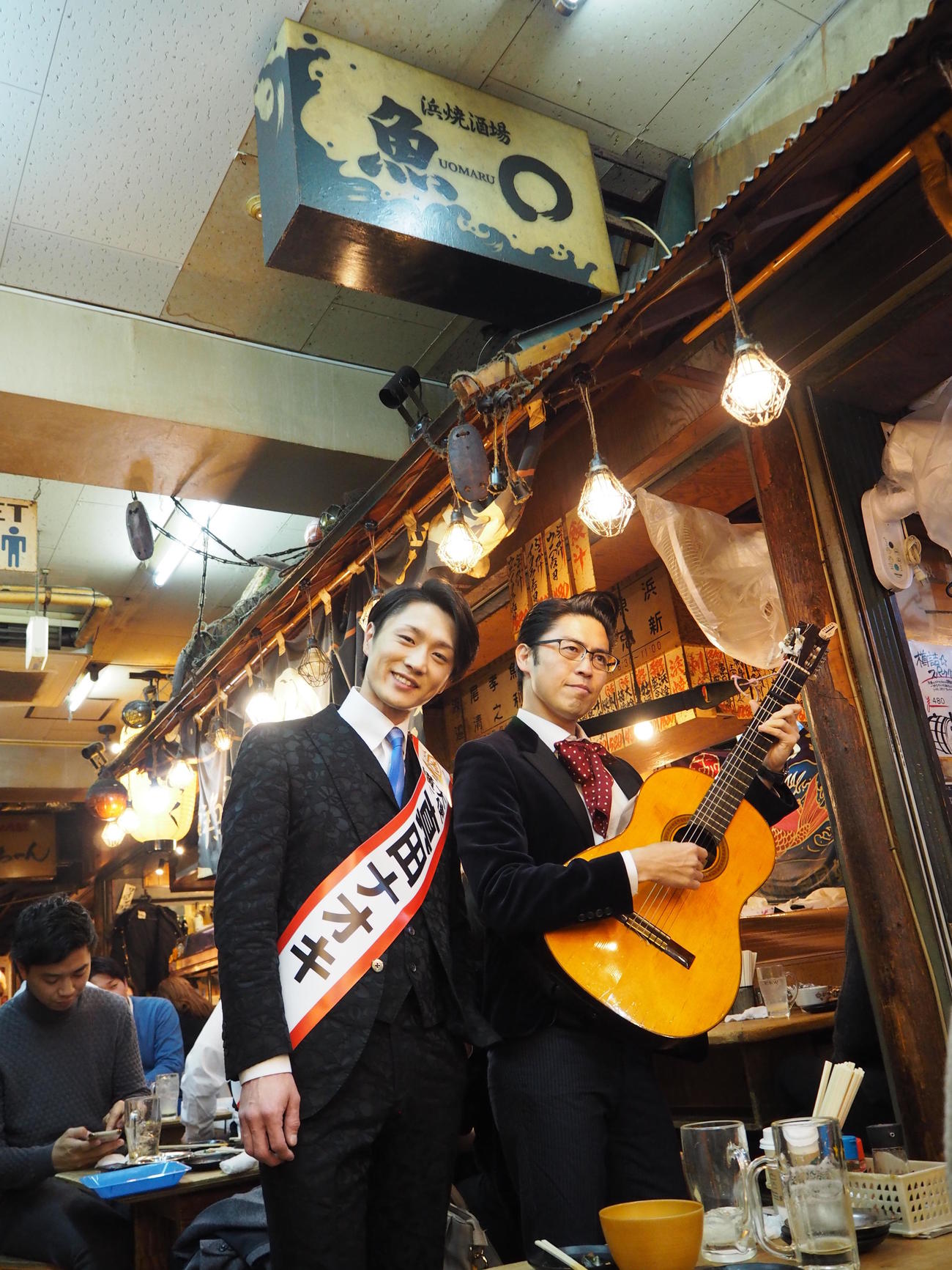 「横丁大使」として恵比寿横丁を前に写真に納まる真田ナオキ（左）