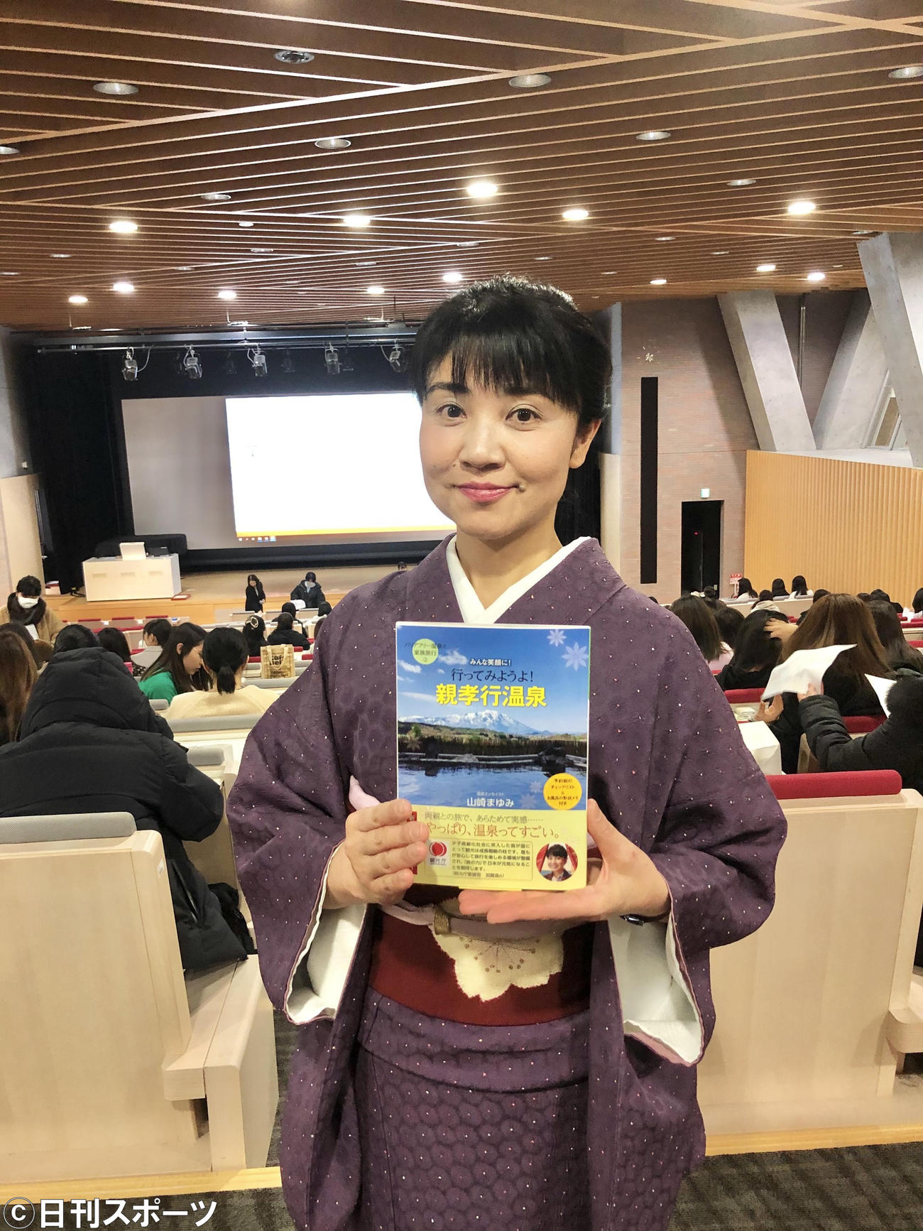 新著「行ってみようよ！親孝行温泉」を手にする山崎まゆみ氏