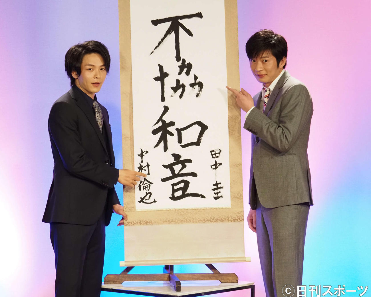 田中圭（左）が「不協」、中村倫也が「和音」を書いた掛け軸の前で記念撮影（撮影・遠藤尚子）