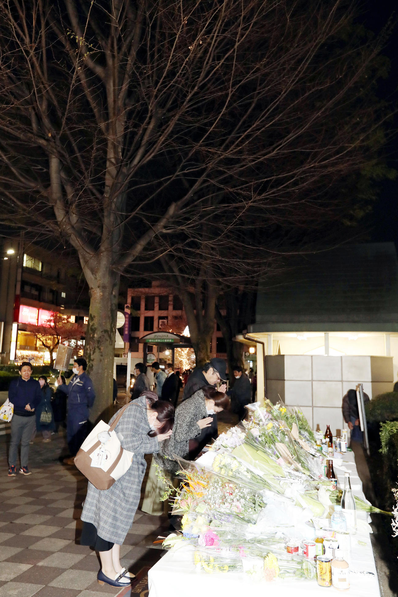 東村山駅前にある「志村けんの木」の前に設置された献花台で手を合わせるファン（撮影・狩俣裕三）