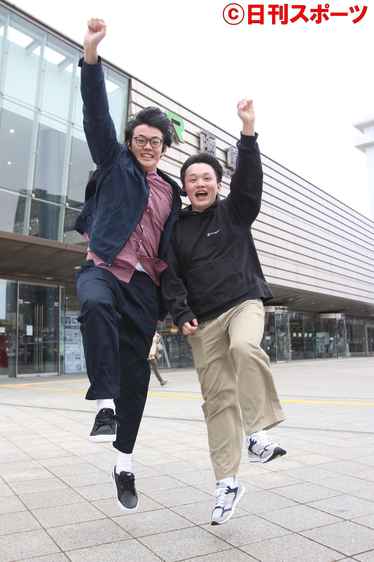 JR函館駅の前でジャンプするダブルグッチーの水口（左）と木戸口