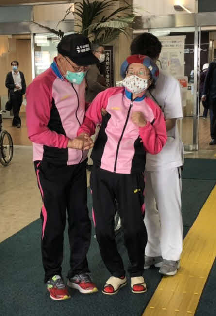 夫の宮川大助（左端）に支えられ立ち上がり、歩いて病院の玄関を出た宮川花子（関係者提供）