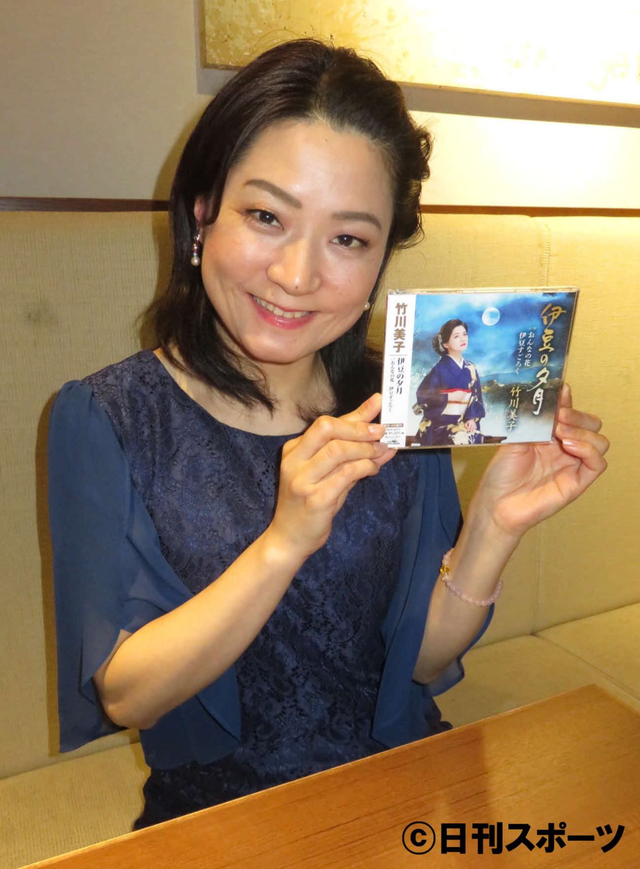 竹川美子は新曲「伊豆の夕月」のCDを手に笑顔