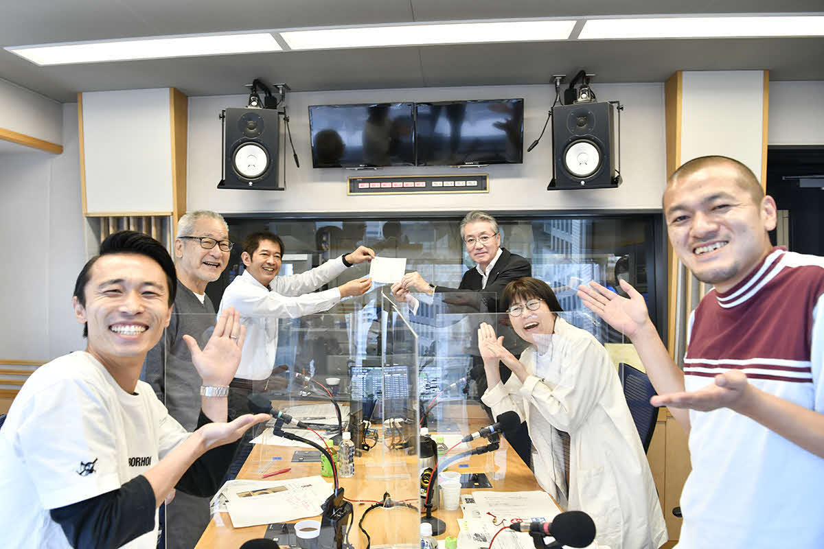 生放送中に上口宏社長（右奥）から辞令交付を受ける太田英明さん（左奥）。共演者（左手前からカミナリ・たくみ、大竹まこと、右手前からカミナリ・まなぶ、光浦靖子）から祝福される（文化放送提供）