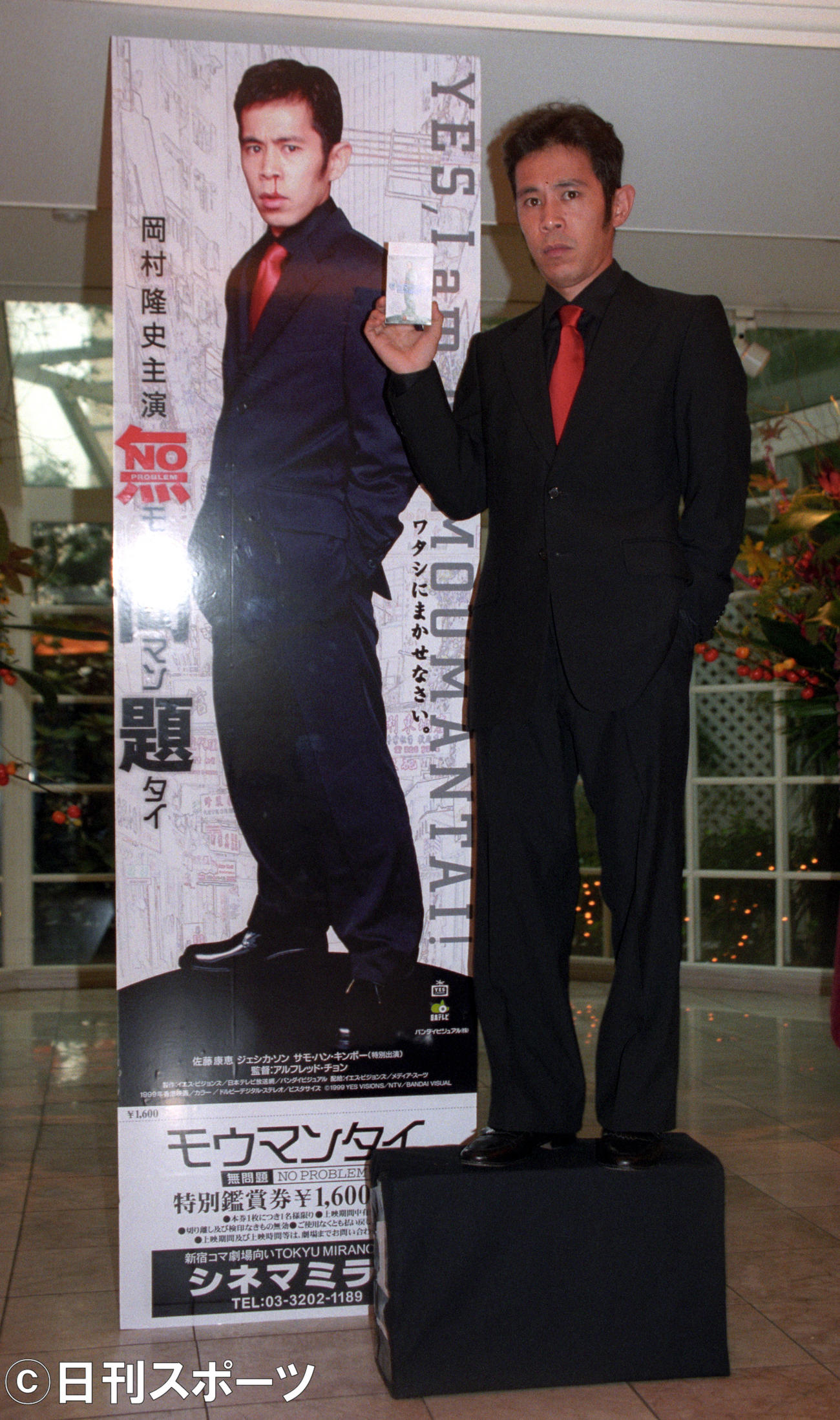 映画「無問題」完成記念特製前売り券　自分の写真が印刷された等身大前売り券と並んでポーズをとる岡村隆史（1999年8月27日）