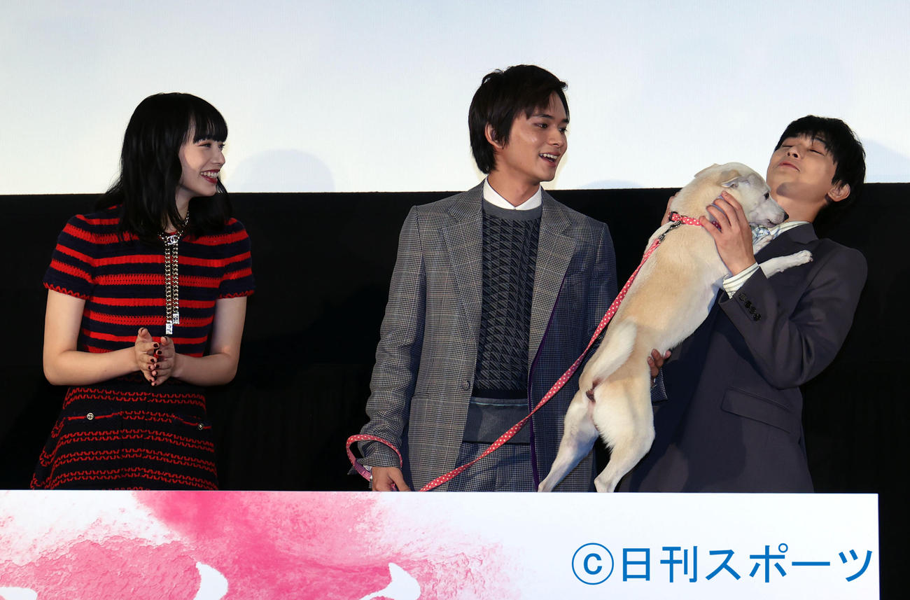 映画「さくら」の舞台あいさつで、さくら役の犬ちえに抱っこをせがまれる吉沢亮（右）。左は小松菜奈、中央は北村匠海（撮影・狩俣裕三）