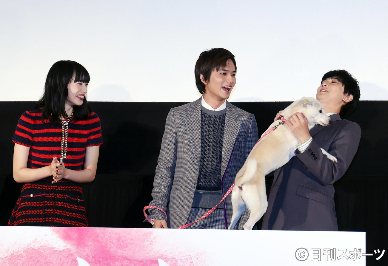 映画「さくら」の舞台あいさつで、さくら役の犬ちえに抱っこをせがまれる吉沢亮（右）。左は小松菜奈、中央は北村匠海（撮影・狩俣裕三）
