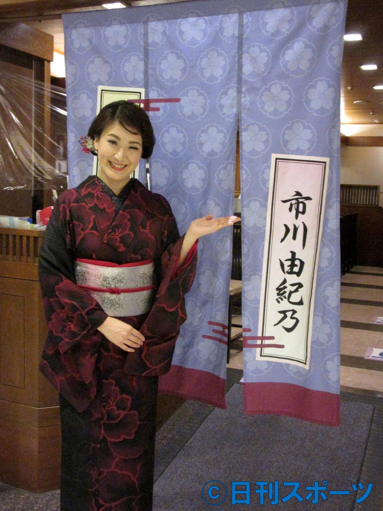 特注ののれんの前に立つ市川由紀（東京・新宿つな八京王店）