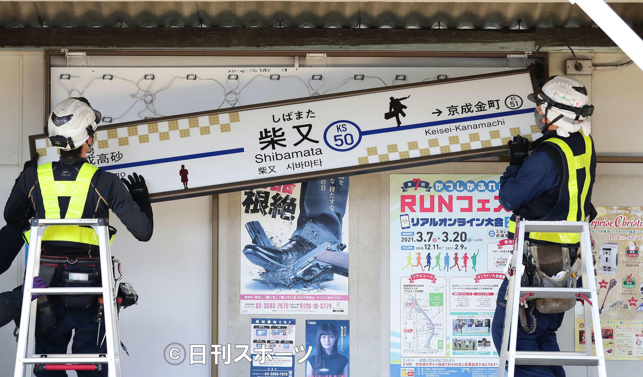 新しくなった駅名看板を設置する作業員（撮影・丹羽敏通）