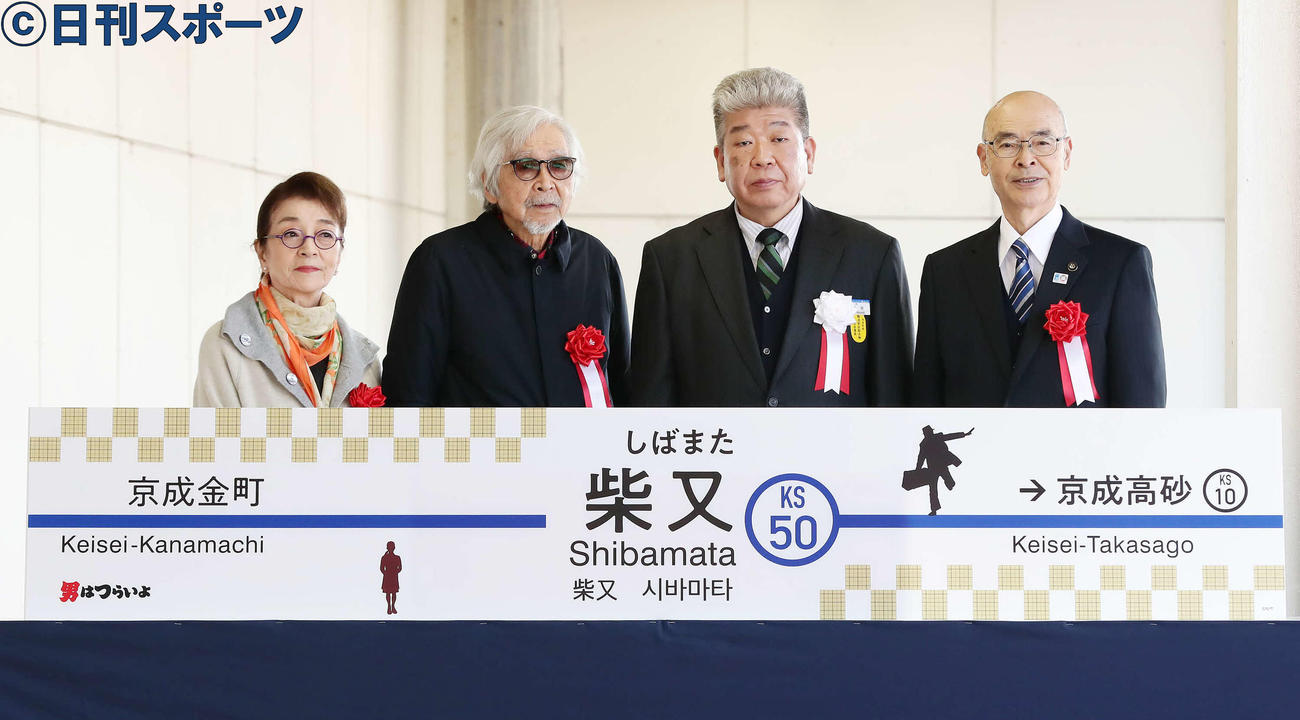 新しくなった駅名看板と写真に納まる、左から倍賞千恵子、山田洋次監督、小林敏也京成電鉄社長、青木克徳葛飾区長（撮影・丹羽敏通）
