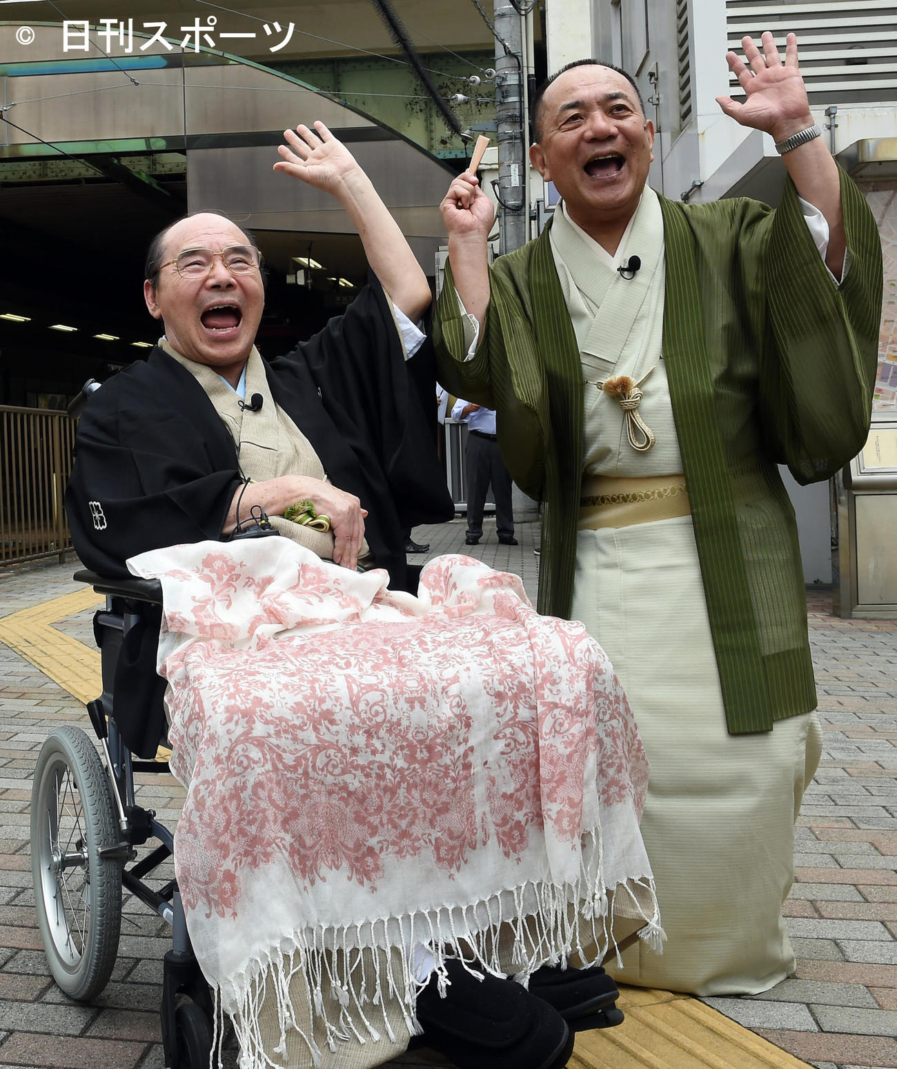 「都電落語会」　都電落語会オープニングセレモニーを終えた林家こん平さん（左）と三遊亭小遊三は、大塚駅前で「チャラーン！」（2014年8月22日）