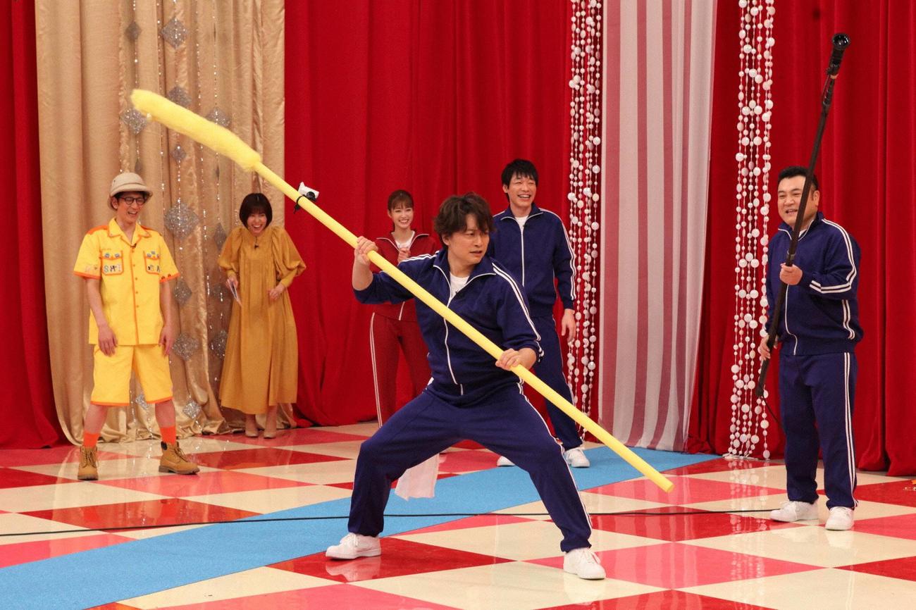 巨大ネコじゃらしを使ってライオンを手なづけようとする香取慎吾（C）フジテレビ
