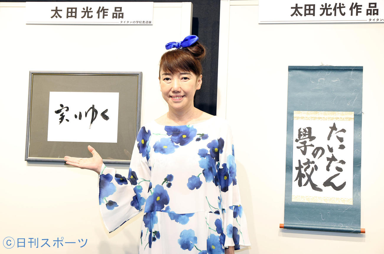 「タイタンの学校　書道展」で、自書「たいたんの学校」と太田光書の「実りゆく」の作品の前でポーズをとる太田光代（撮影・浅見桂子）