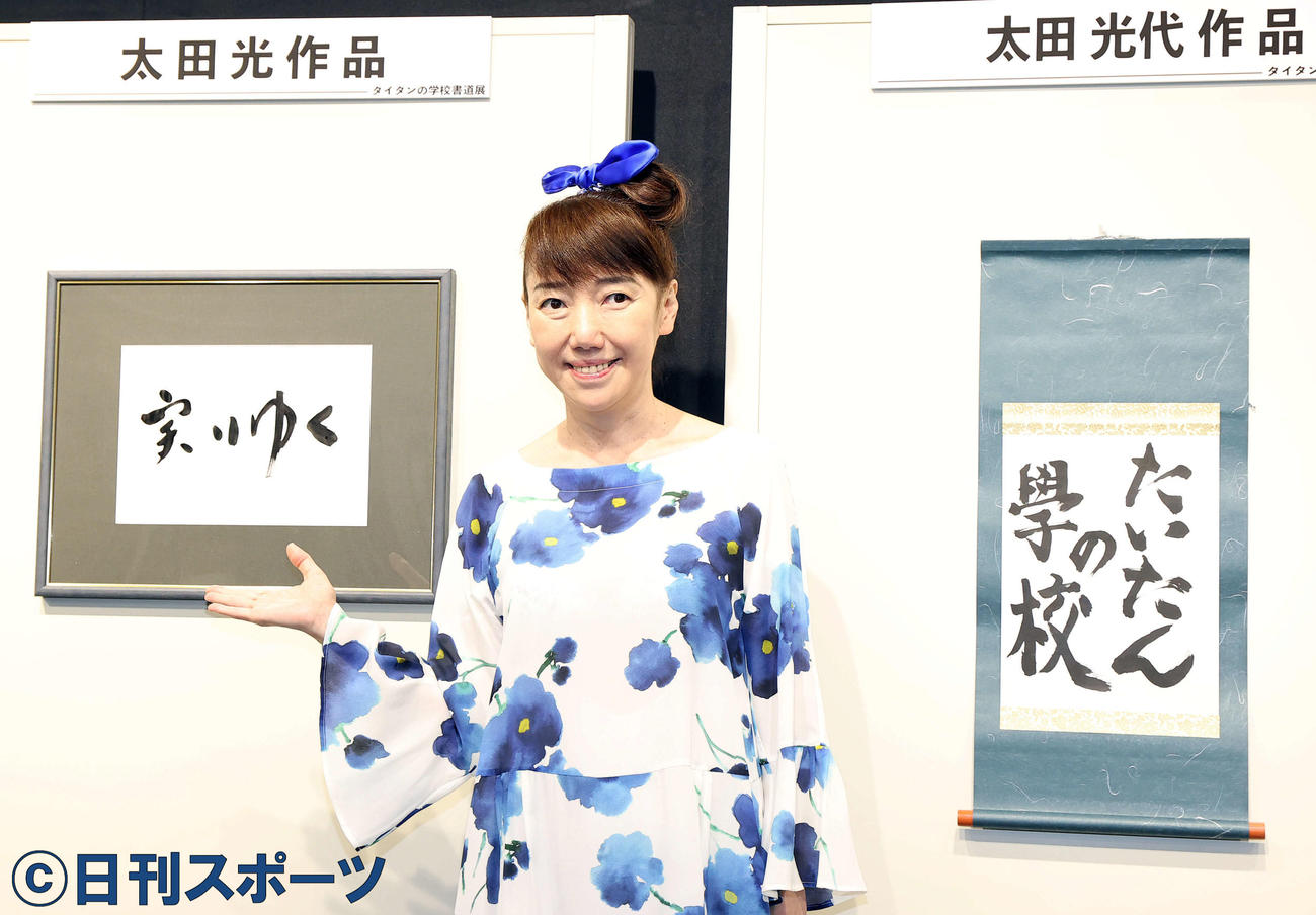 「タイタンの学校　書道展」で展示された作品を背にポーズをとる太田光代氏（撮影・浅見桂子）