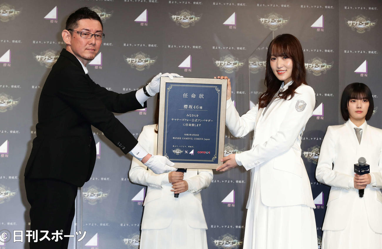 「サマナーズウォー×櫻坂46」7周年記念の公式アンバサダー任命式でGAMEVIL COM2US Japanの矢野寛事業室長（左）から任命状を受け取る櫻坂46の菅井友香（撮影・丹羽敏通）