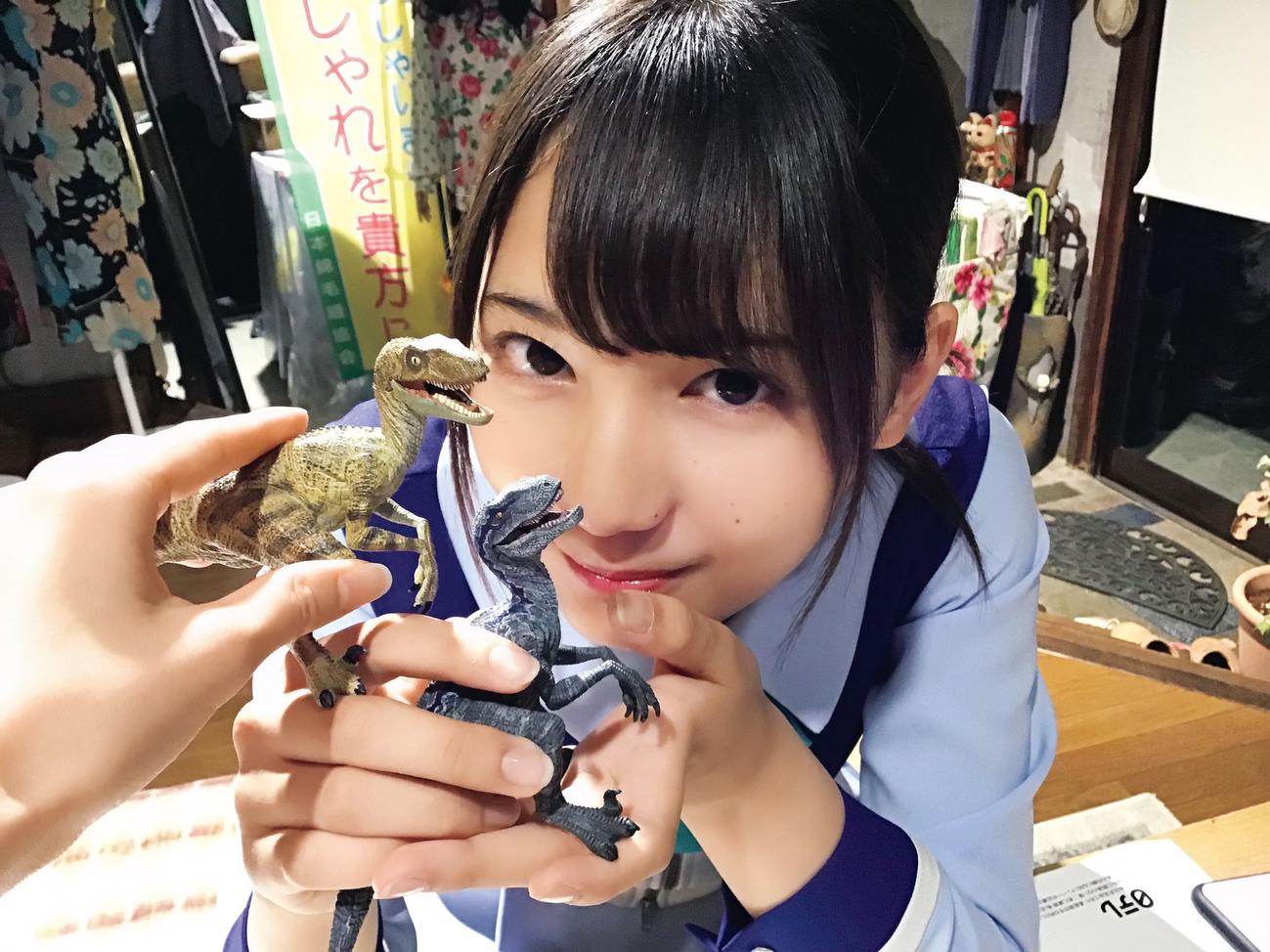 「日向撮」先行カット。恐竜のフィギュアを持って笑顔を見せる小坂菜緒。齊藤京子が撮影した