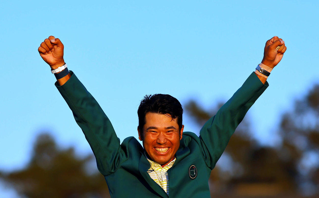 米ゴルフのマスターズ・トーナメントで、日本男子初のメジャー制覇を果たし、グリーンジャケットを着て両手を上げる松山（ロイター）