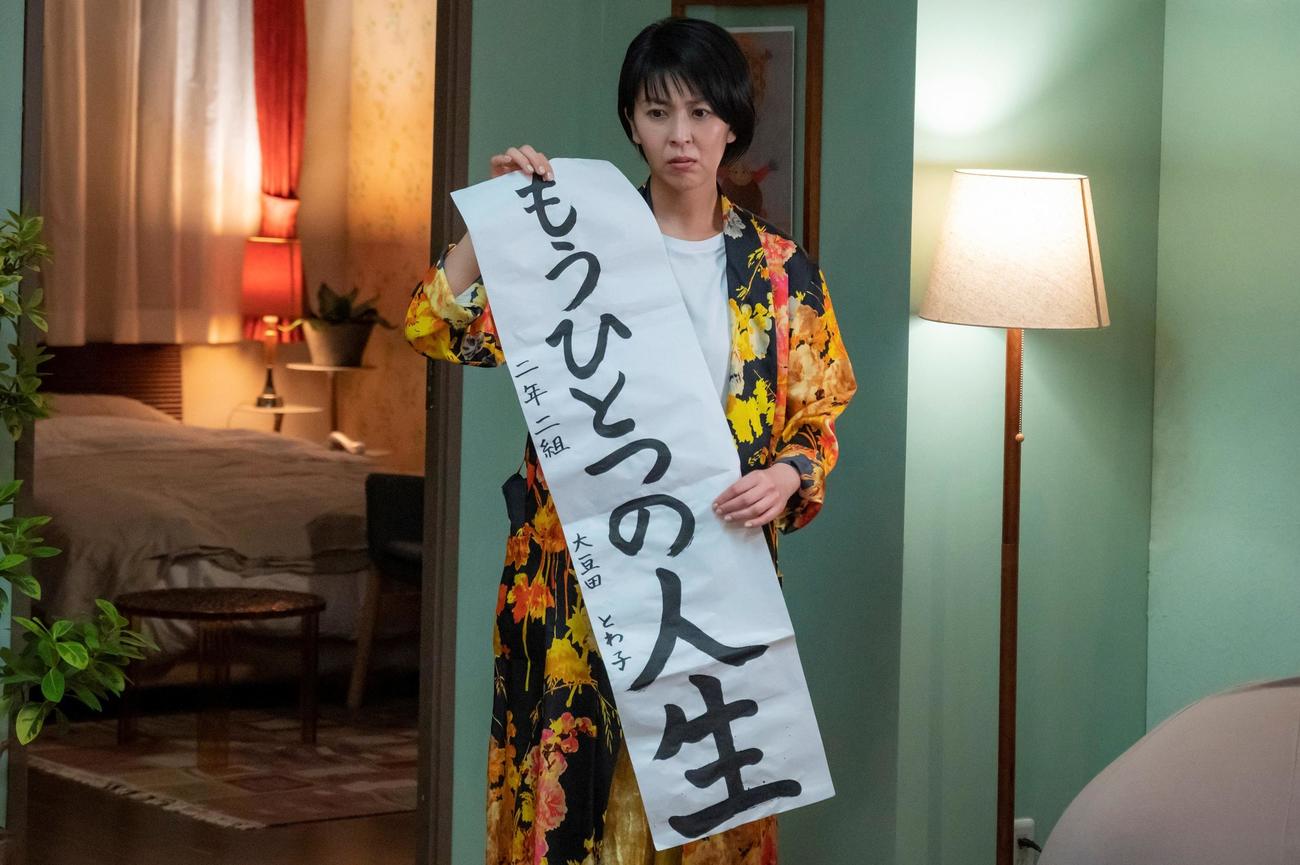 自分の書いた習字を手にする大豆田とわ子（C）カンテレ