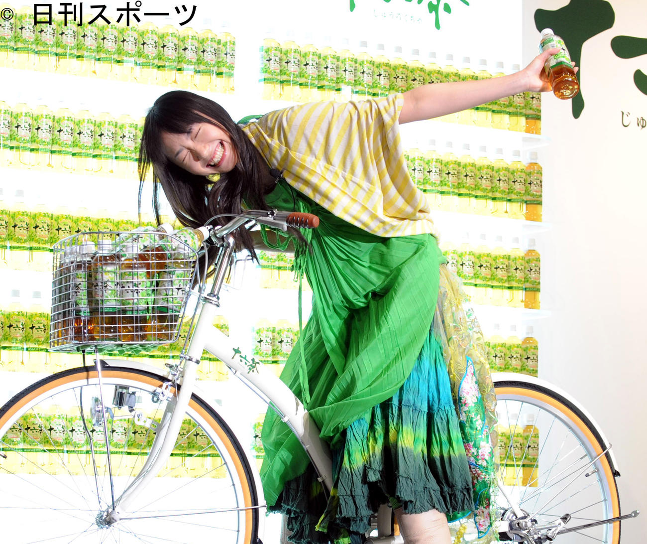 十六茶新CM発表会に自転車に乗って登壇した20歳の新垣結衣は坂道でよろめき、照れ隠しの笑顔を見せる（2009年3月）