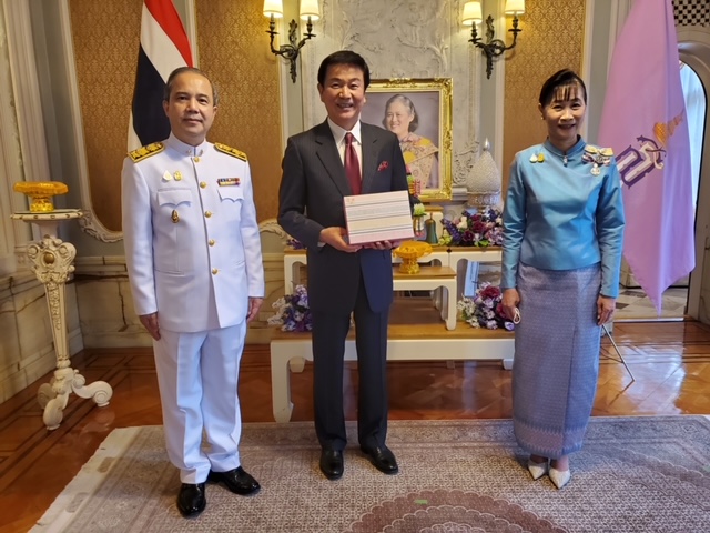 タイのシントン・ラーピセートパン日本大使夫妻から、シリントーン王女からの御下賜品を授与された森田健作（中央）