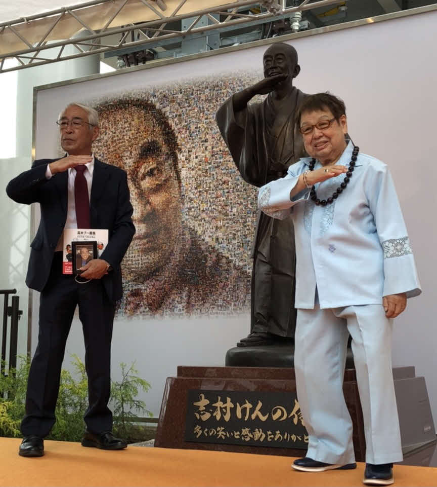 志村けんさんの銅像の前で、アイーンのポーズをとる高木ブー（右）と志村さんの兄知之さん