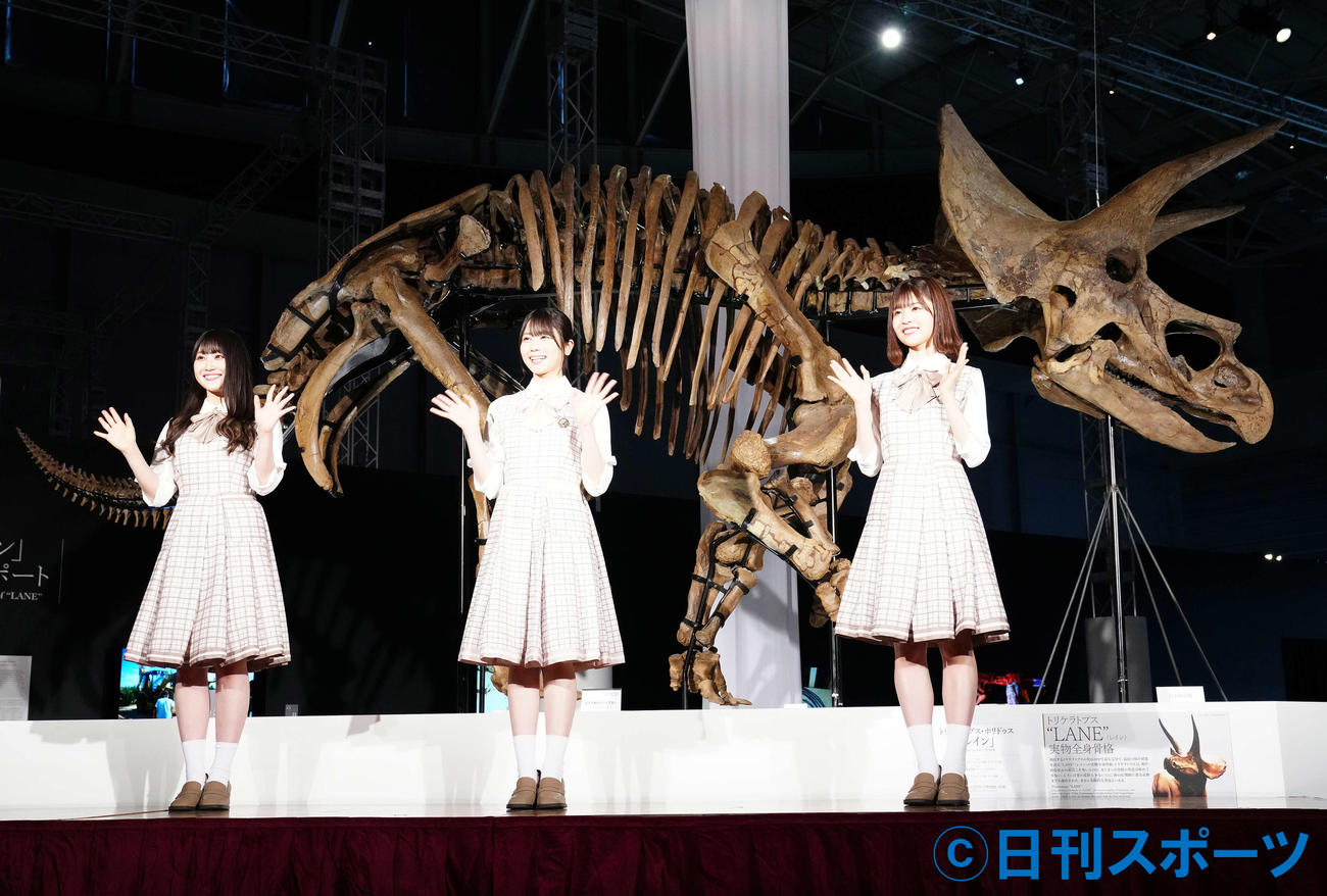 「恐竜科学博」に展示されるトリケラトプスの実物全身骨格「レイン」を背に写真に納まる日向坂46の、左から潮紗理菜、丹生明里、松田好花（撮影・江口和貴）