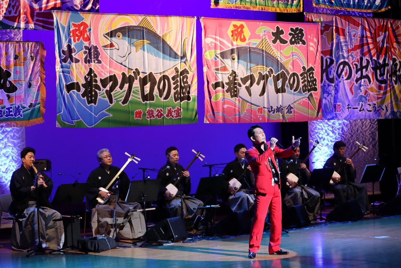 大漁旗をバックに熱唱する福田こうへい
