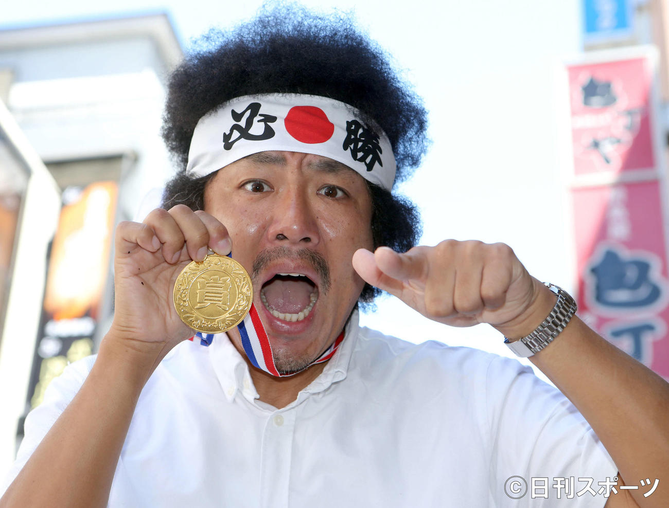「必勝」の鉢巻きで、金メダルを片手にポーズを取るトータルテンボス藤田憲右（撮影・勝部晃多）