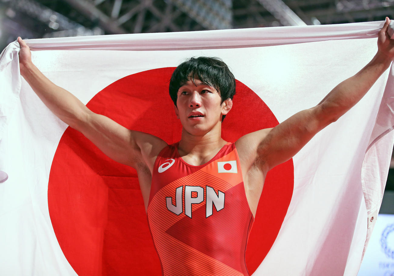 男子フリースタイル65キロ級決勝を制し目を潤ませながら日の丸を掲げる乙黒拓斗（撮影・パオロ・ヌッチ）
