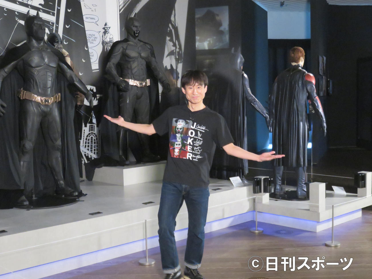「DC展　スーパーヒーローの誕生」の展示品の前でポーズを取るなだぎ武