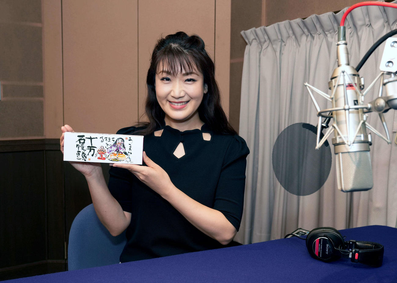 十万石まんじゅうを手に取り、笑顔の市川由紀乃