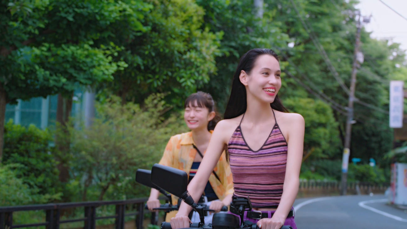 「Tinder」新オンラインCM「キックボード」編でキックボードに乗る水原希子（手前）