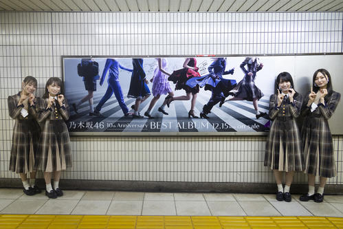 YouTubeの生配信で乃木坂駅を訪れ、ベストアルバムのポスターを前に笑顔を見せる乃木坂46。左から北野日奈子、秋元真夏、賀喜遥香、梅澤美波