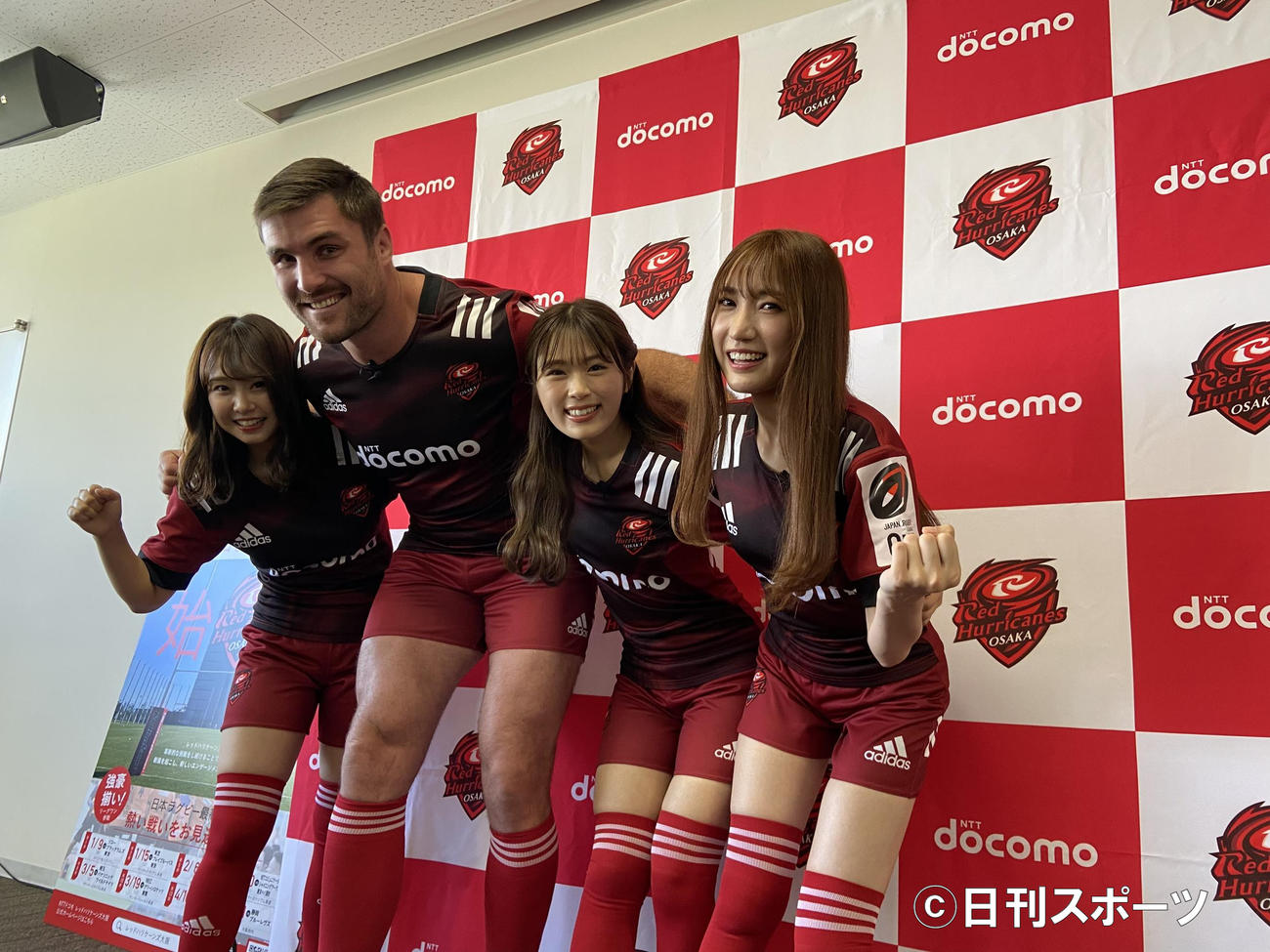 NTTドコモレッドハリケーンズ大阪の公式アンバサダーに就任したNMB48の加藤夕夏（左）、渋谷凪咲（右から2人目）、原かれん（右）はエラスマス主将とスクラムを組む（撮影・松本航）