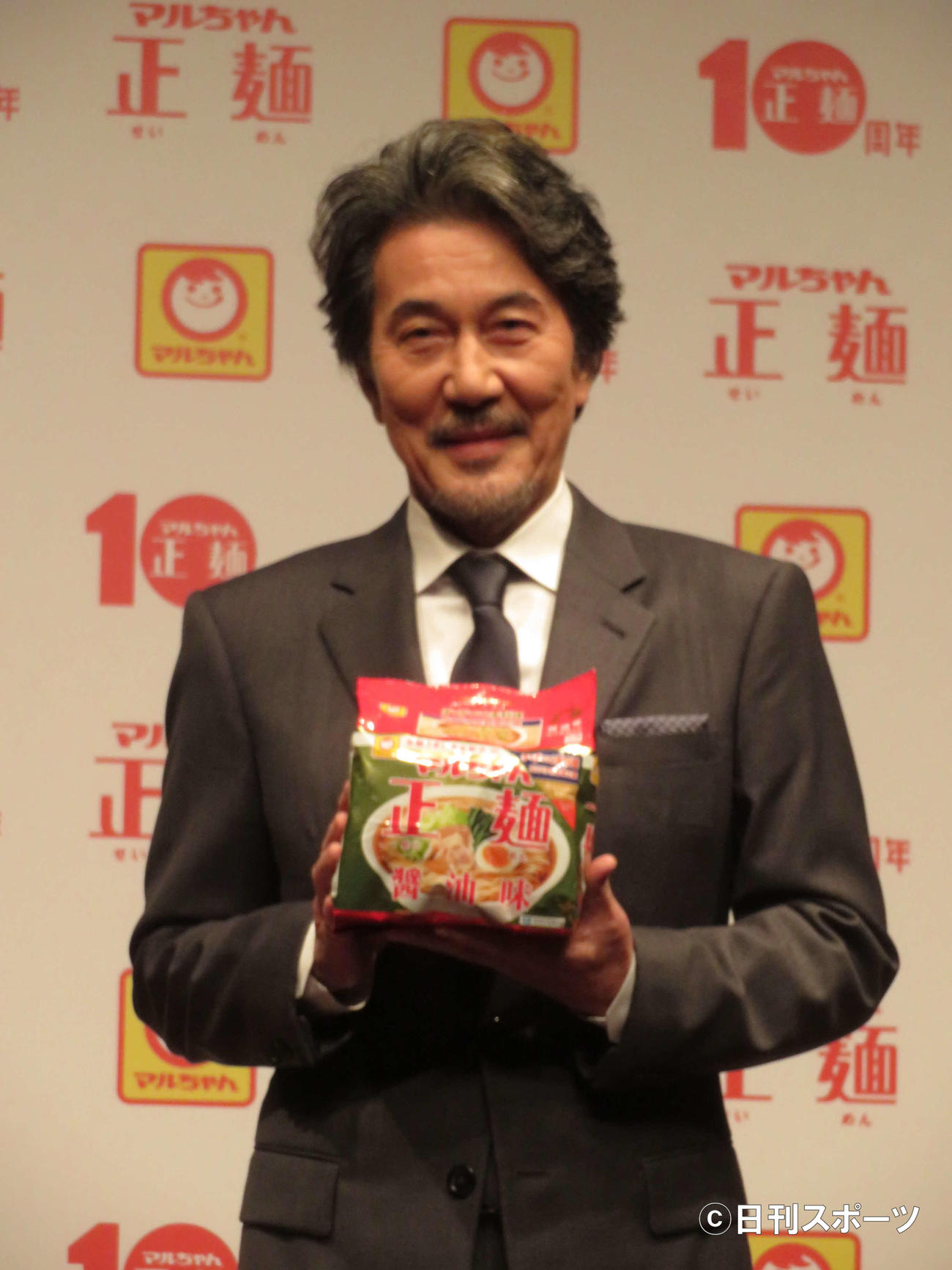 「マルちゃん正麺　10周年記念発表会」でマルちゃん正麺を手に、笑顔の役所広司（撮影・村上幸将）