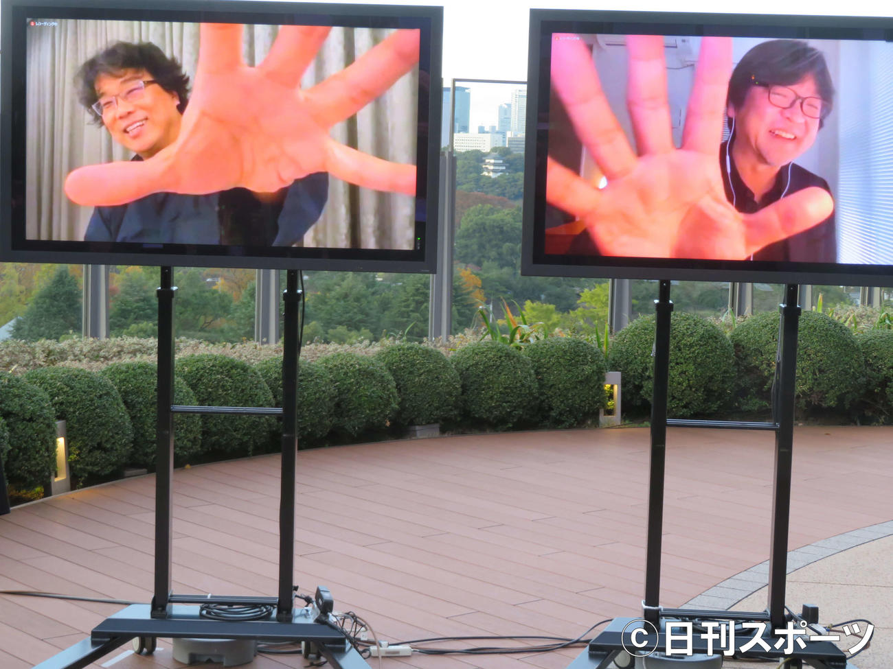 東京国際映画祭「トークシリーズ＠アジア交流ラウンジ」でオンラインで対談後、画面に手を広げるパフォーマンスをするポン・ジュノ監督（左）と細田守監督（撮影・村上幸将）