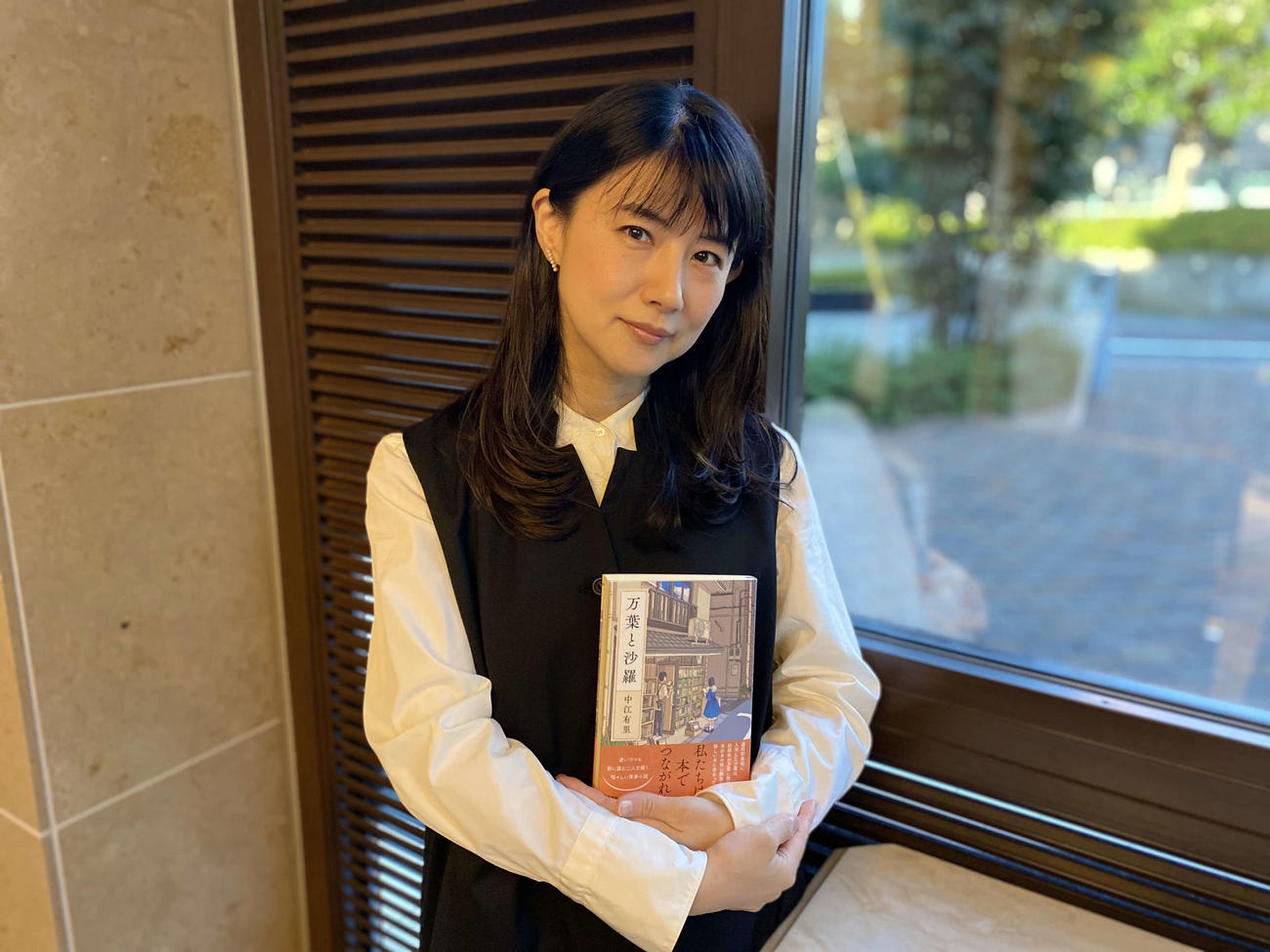 小説「万葉と沙羅」を手にする中江有里