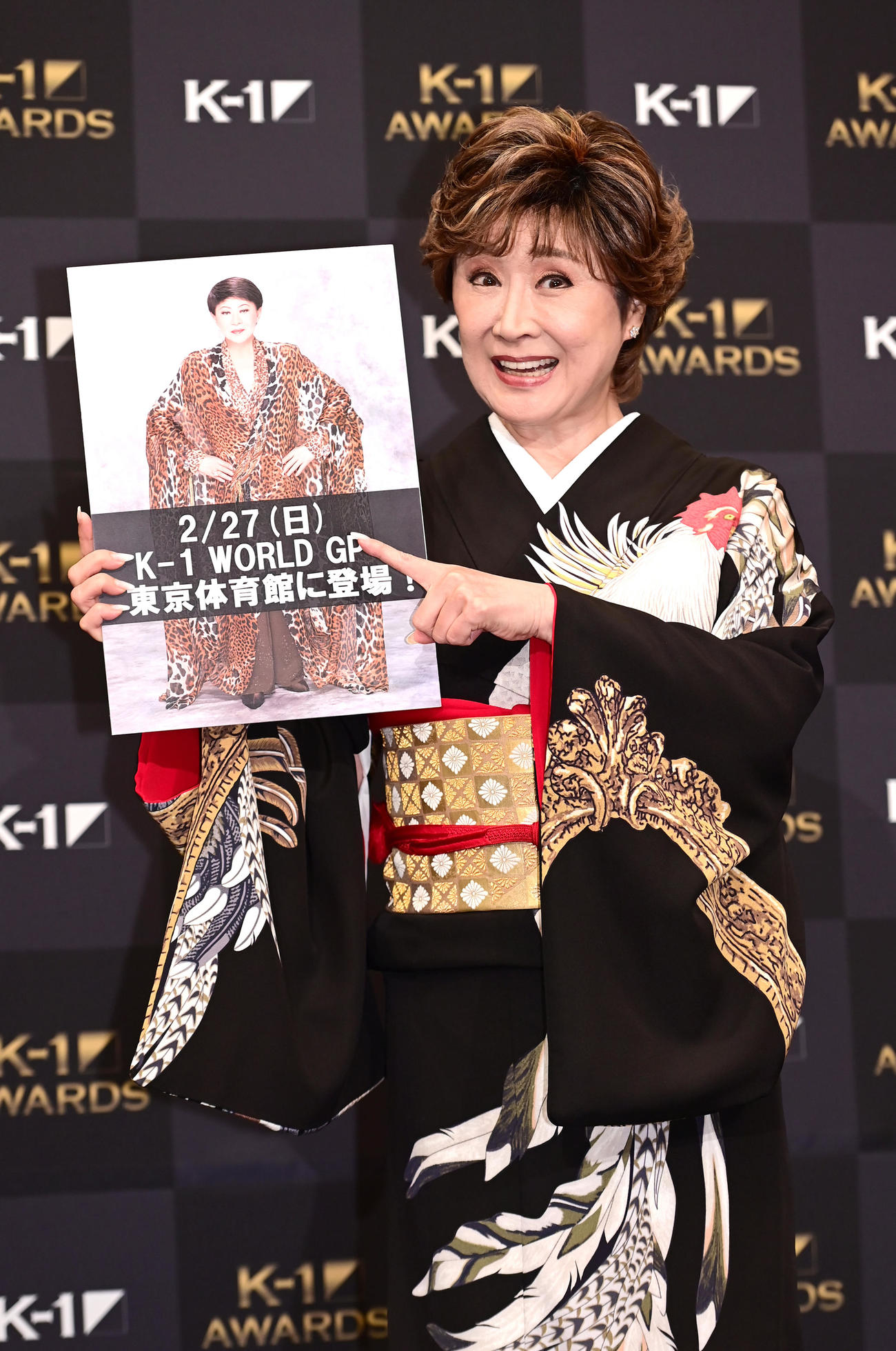 「K－1 AWARDS（アウォーズ）2021」でプレゼンターを務めた小林幸子はラウンドガールに挑戦する美川憲一のボードを手に笑顔を見せる（撮影・小沢裕）