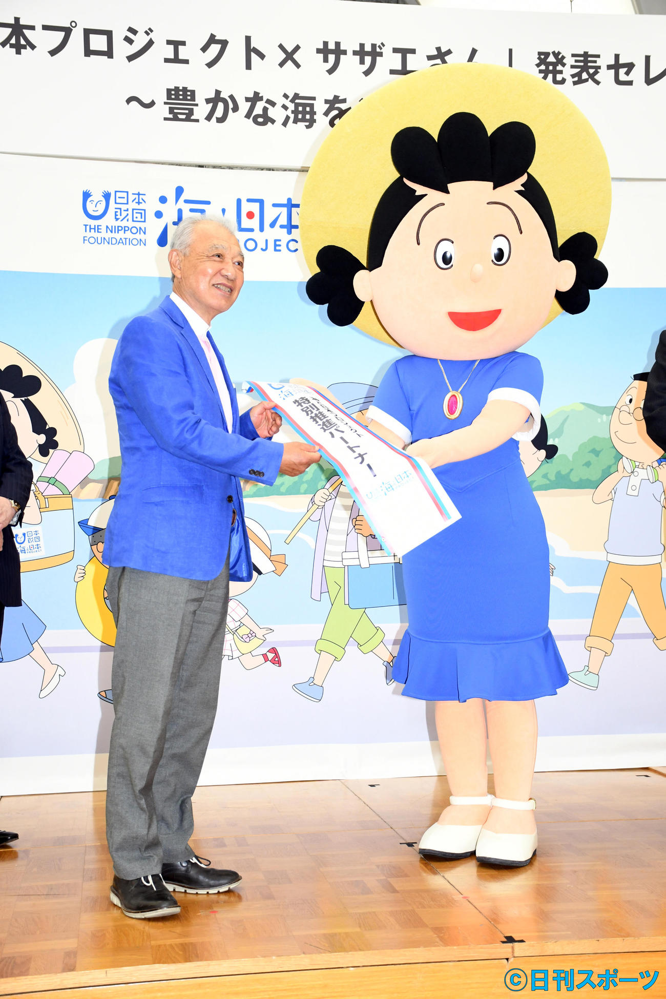 「海と日本プロジェクト×サザエさん」発表セレモニーで日本財団笹川陽平会長からたすきを受け取るサザエさん（撮影・大友陽平）