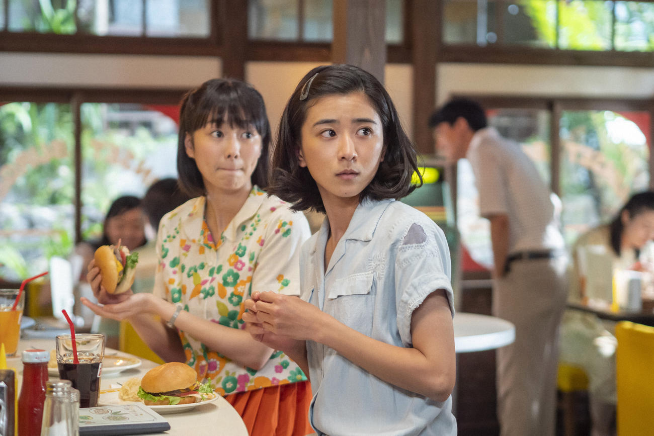 朝ドラ「ちむどんどん」より。ハンバーガーショップで何かに気づいて振り返る比嘉暢子（右＝黒島結菜）と友人の前田早苗（高田夏帆）（C）NHK
