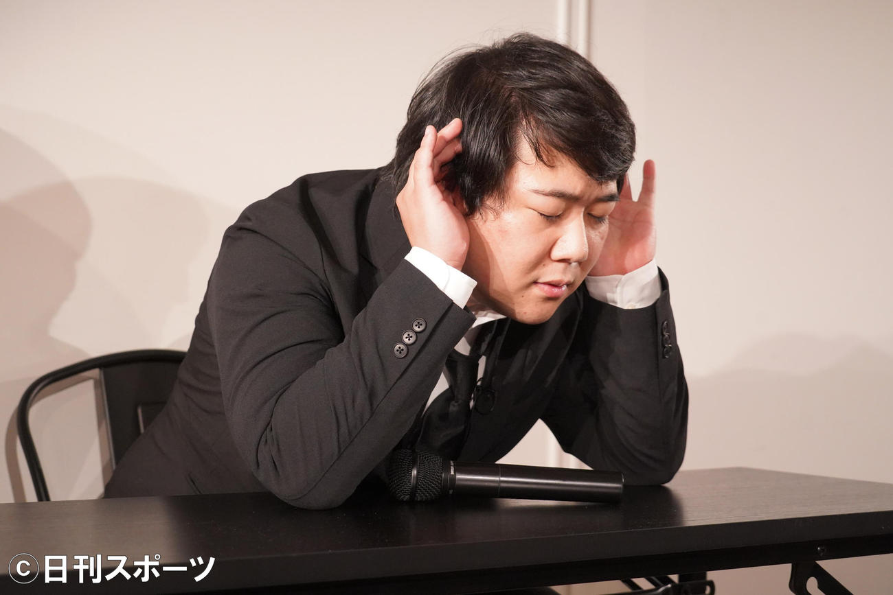 質問を聞こうと両耳に手を当てるニシダ（撮影・佐藤成）