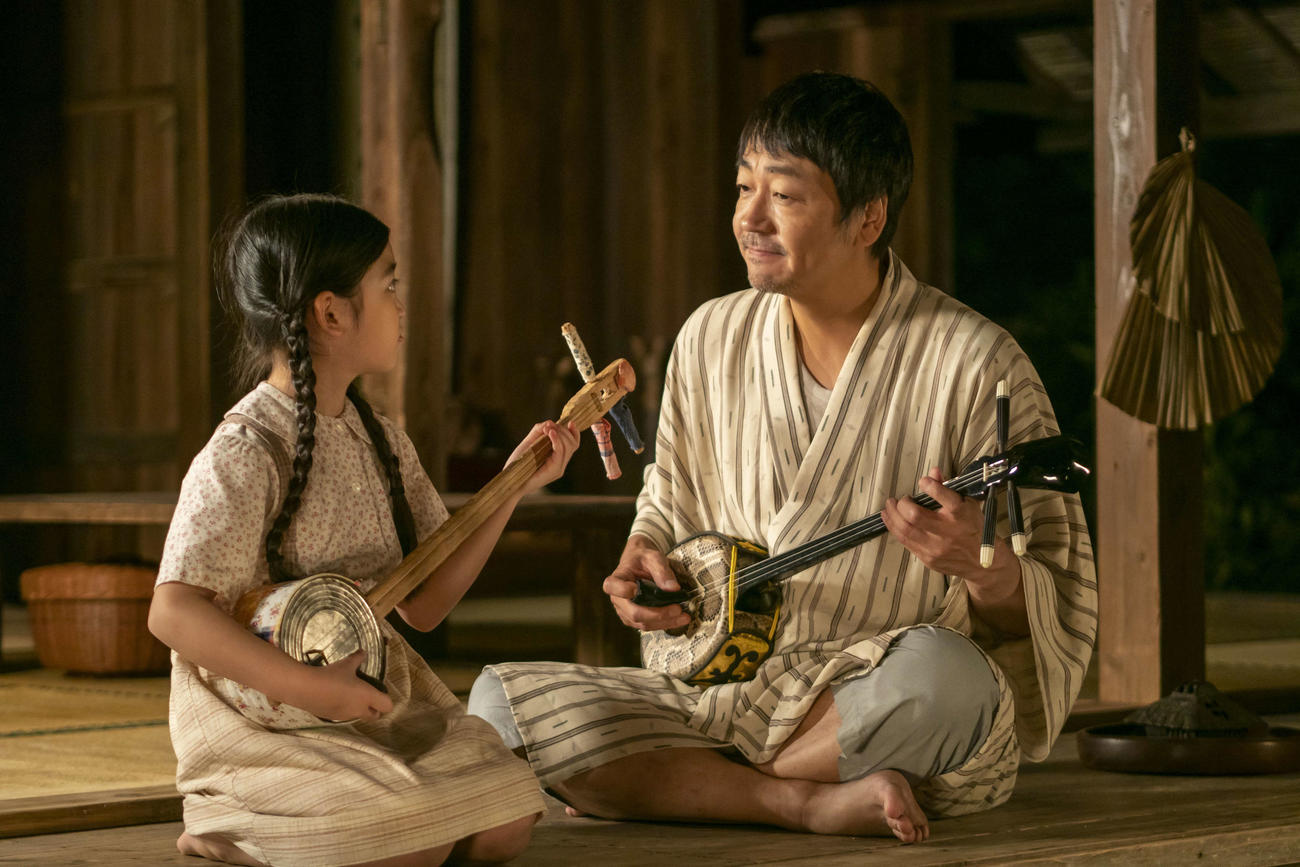 父賢三（大森南朋）と三線を演奏する歌子（布施愛織）（C）NHK