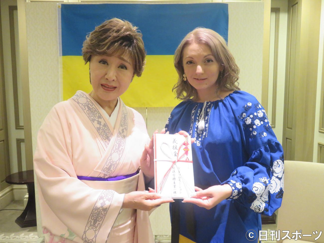 小林幸子（左）はカテリーナに義援金を渡す