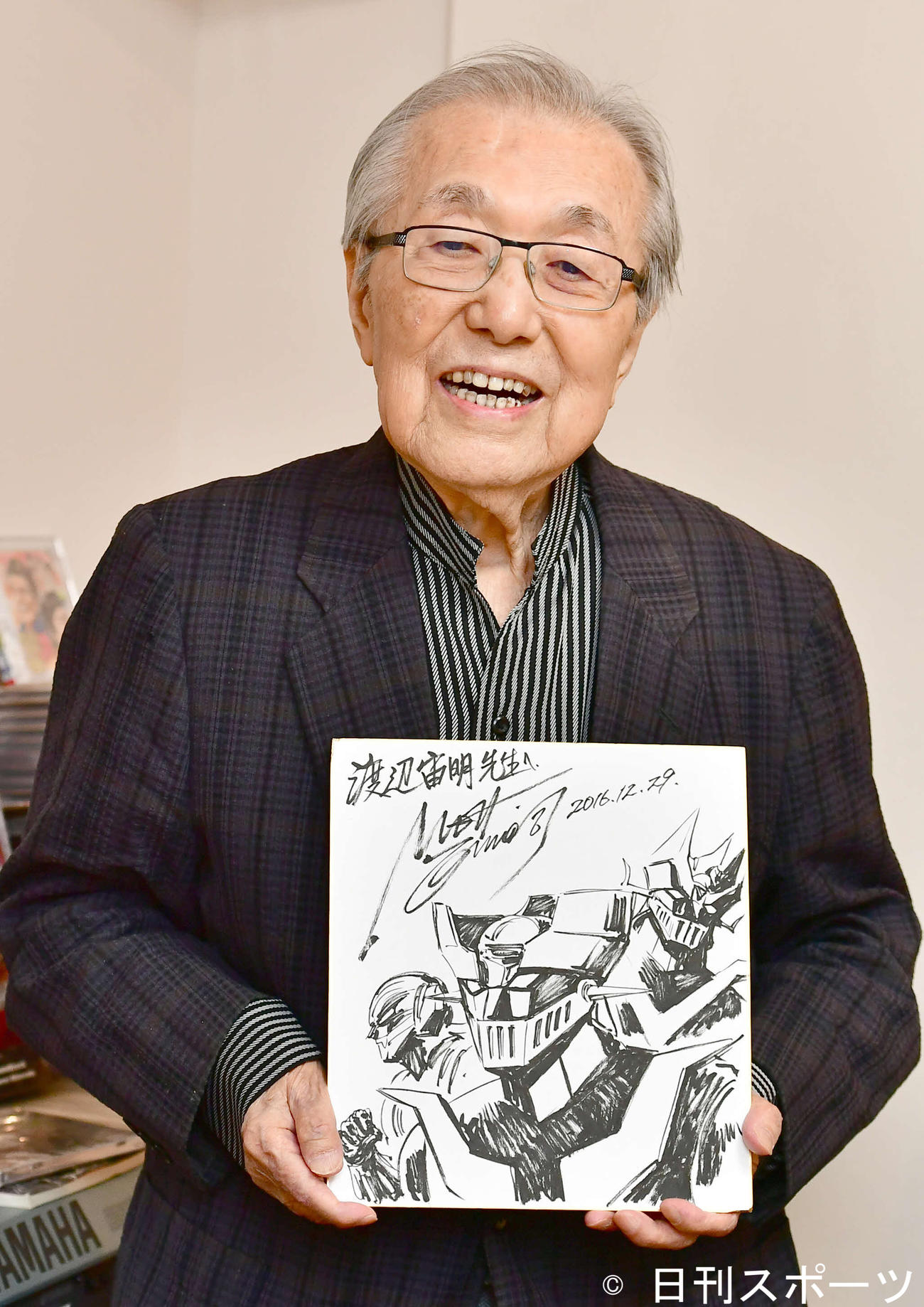 18年3月、アニメ「マジンガーZ」の色紙を手に笑顔を見せる作曲家の渡辺宙明氏