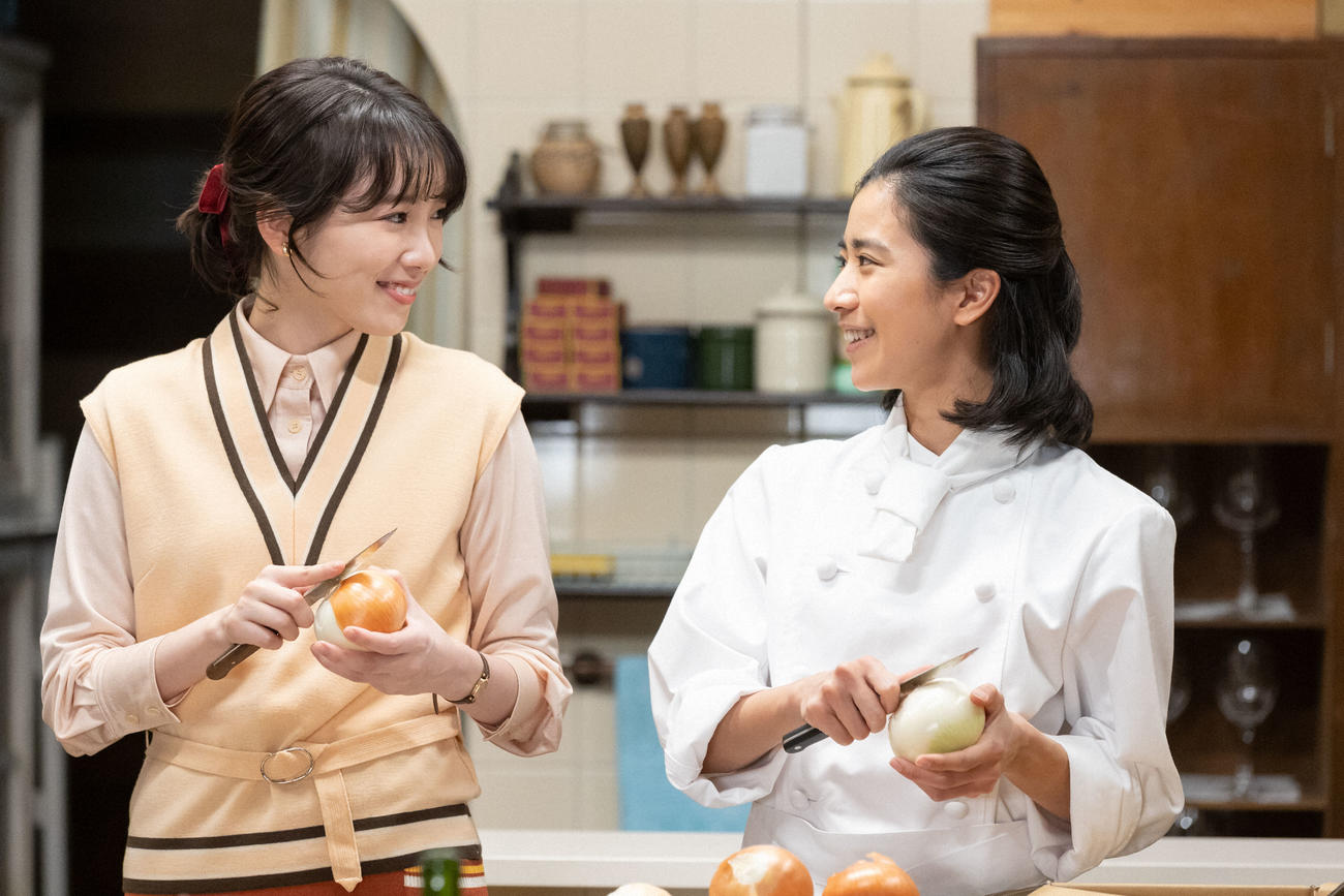 朝ドラ「ちむどんどん」より。イタリア料理店フォンターナの厨房で笑顔で話す大野愛（左＝飯豊まりえ）と比嘉暢子（黒島結菜）(C)NHK