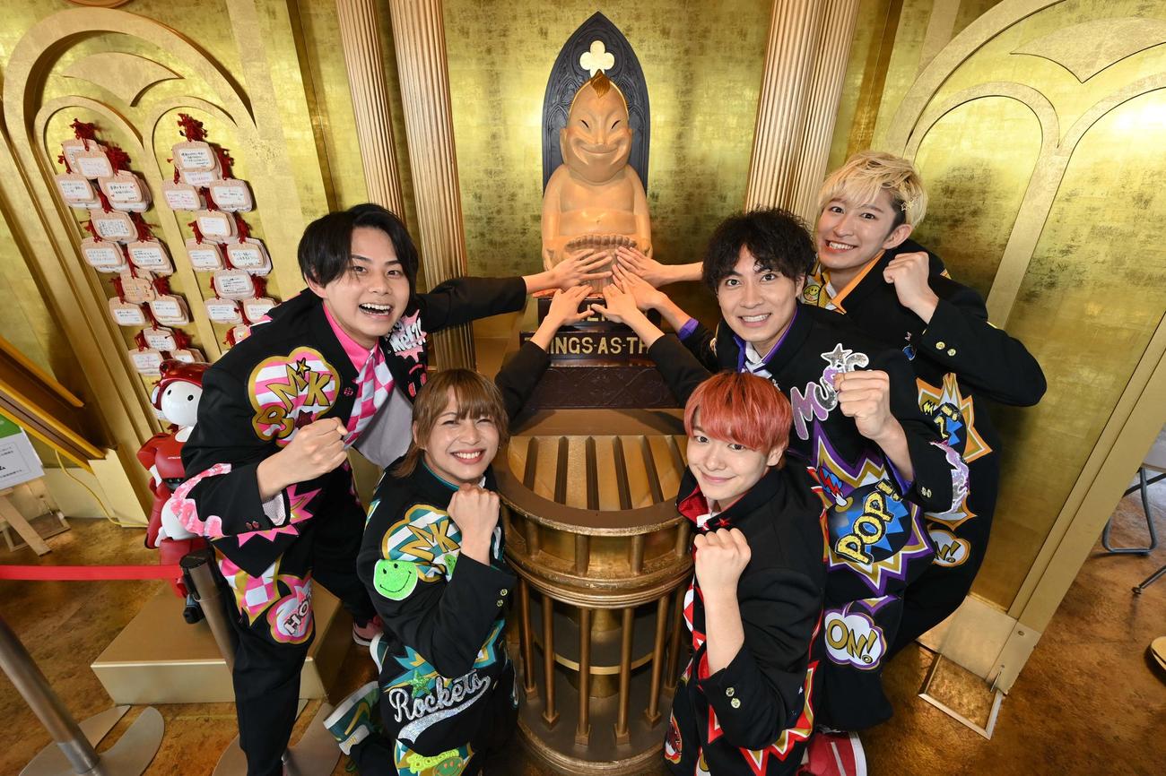 通天閣で祈願し、ビリケンさんの足の裏をなでるBMKメンバー