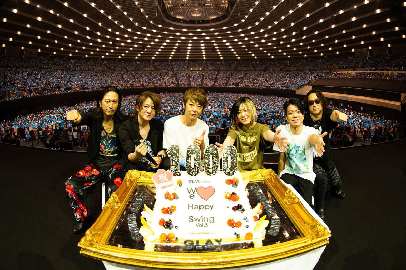1000回目のライブを祝うケーキを前に笑顔のメンバー。左からGLAYのTAKURO、TERU、JIRO、HISASHIとサポートメンバーの2人