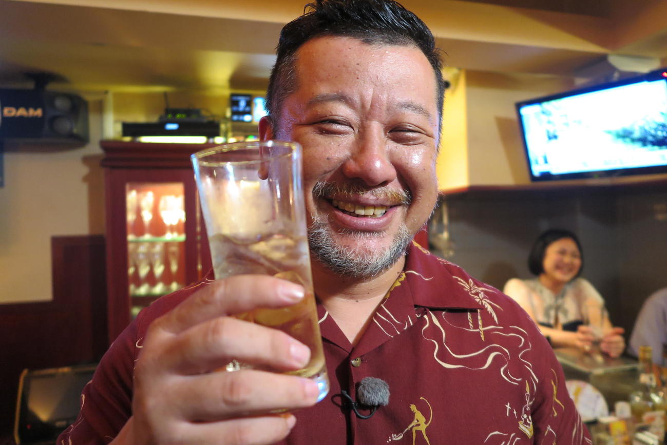 笑顔で酒のグラスを持つケンドーコバヤシ