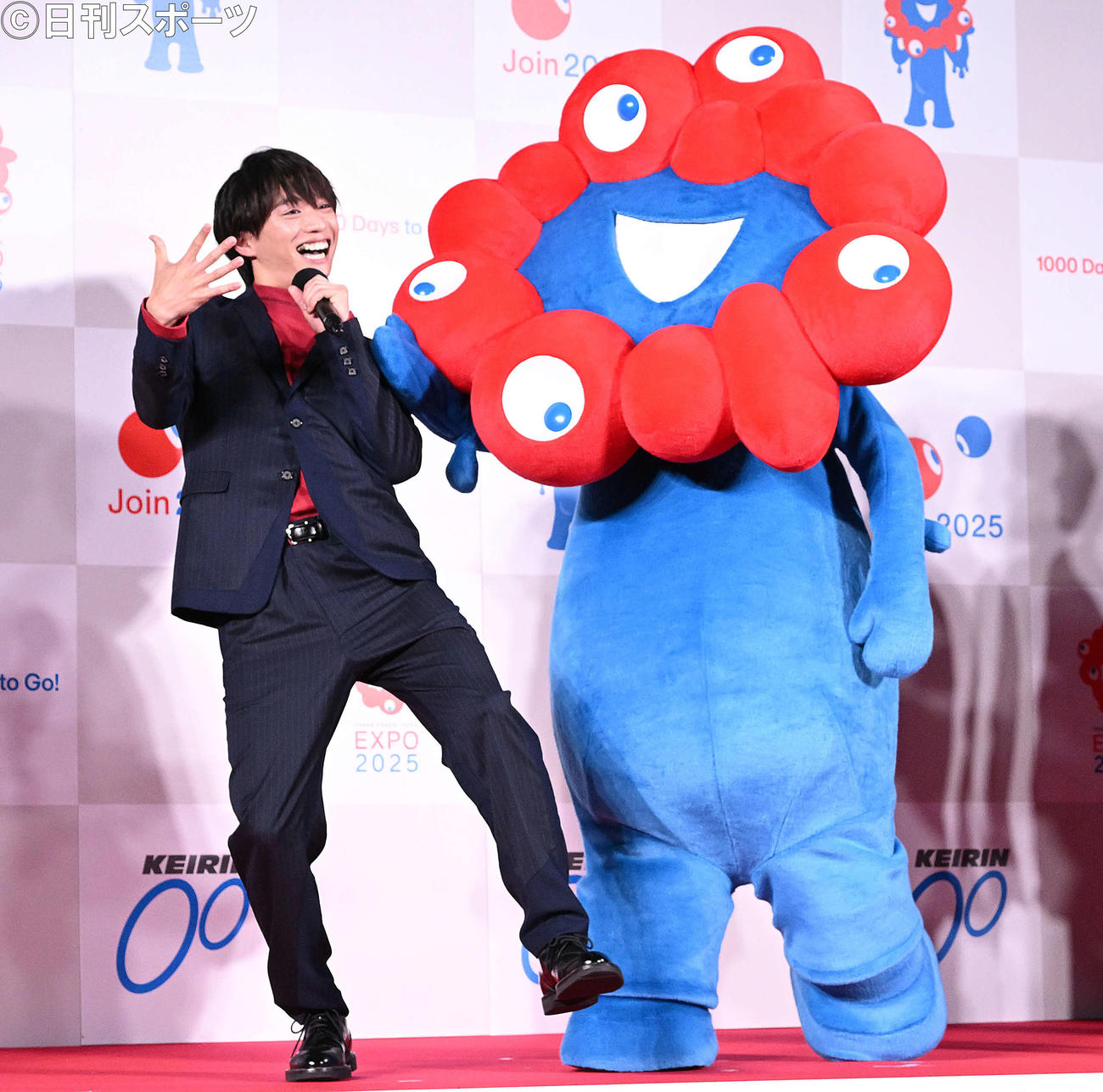 Aえ！　groupの福本大晴は一発ギャグを披露し公式キャラクターのミャクミャクからつっこまれる（撮影・滝沢徹郎）