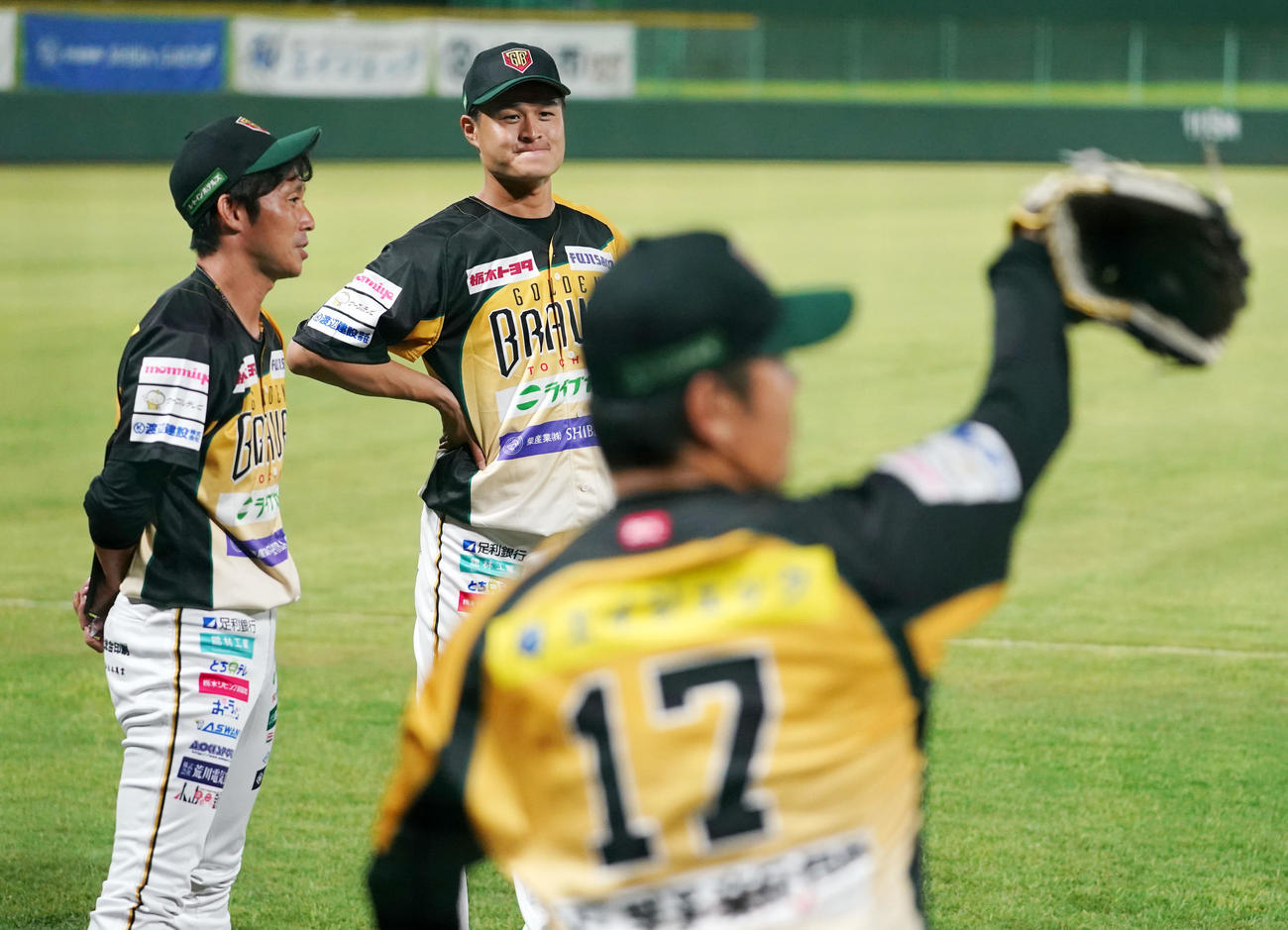 栃木対茨城　栃木・成瀬選手兼投手総合コーチ（右）の投球練習を見つめるティモンディの高岸宏行（中央）。左は吉川選手兼投手コーチ（撮影・横山健太）